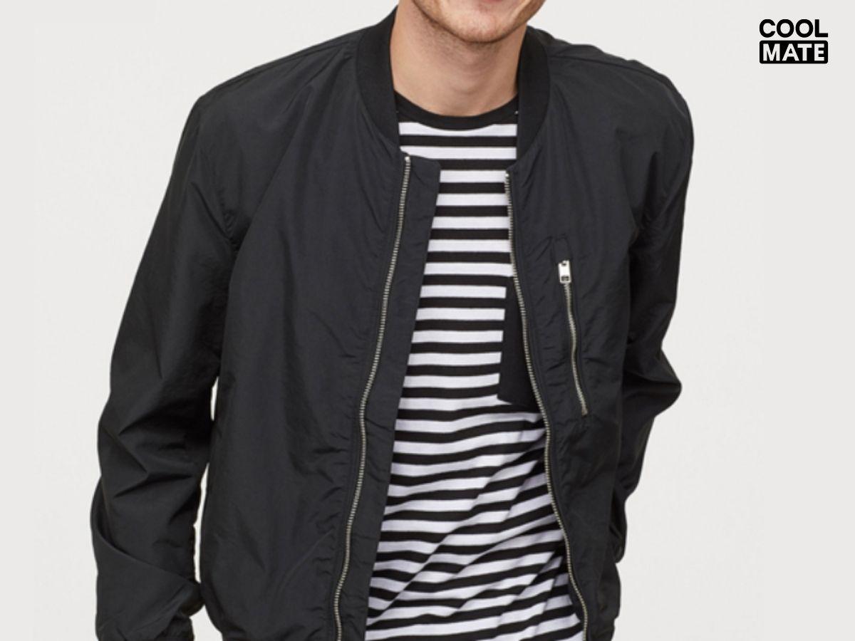 Áo bomber jacket màu đen, lộ rõ phần khóa kéo và phần cổ bo chun