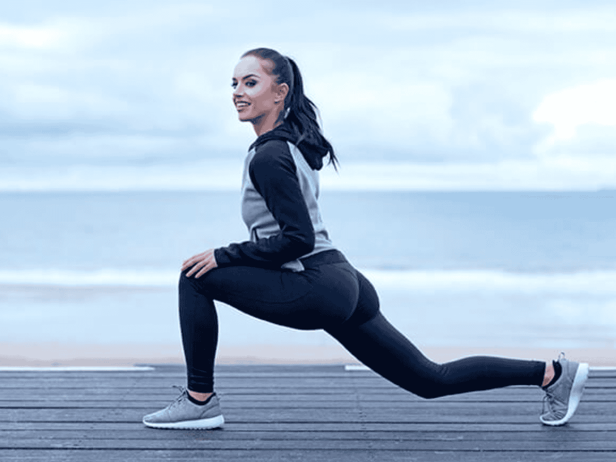 Ép chân về phía lưng là bài tập khởi động trước khi chạy bộ thể thao